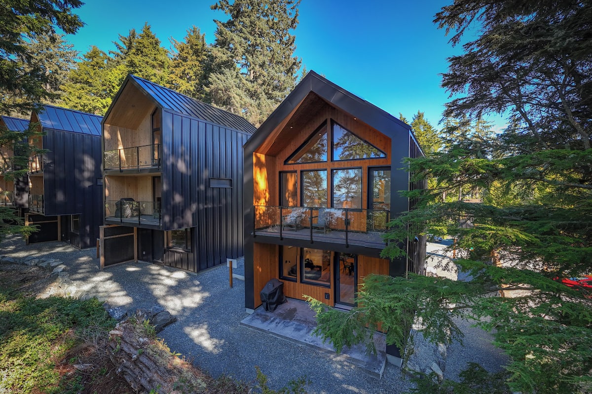 A modern cabin with a wooden exterior, large windows, and a balcony.