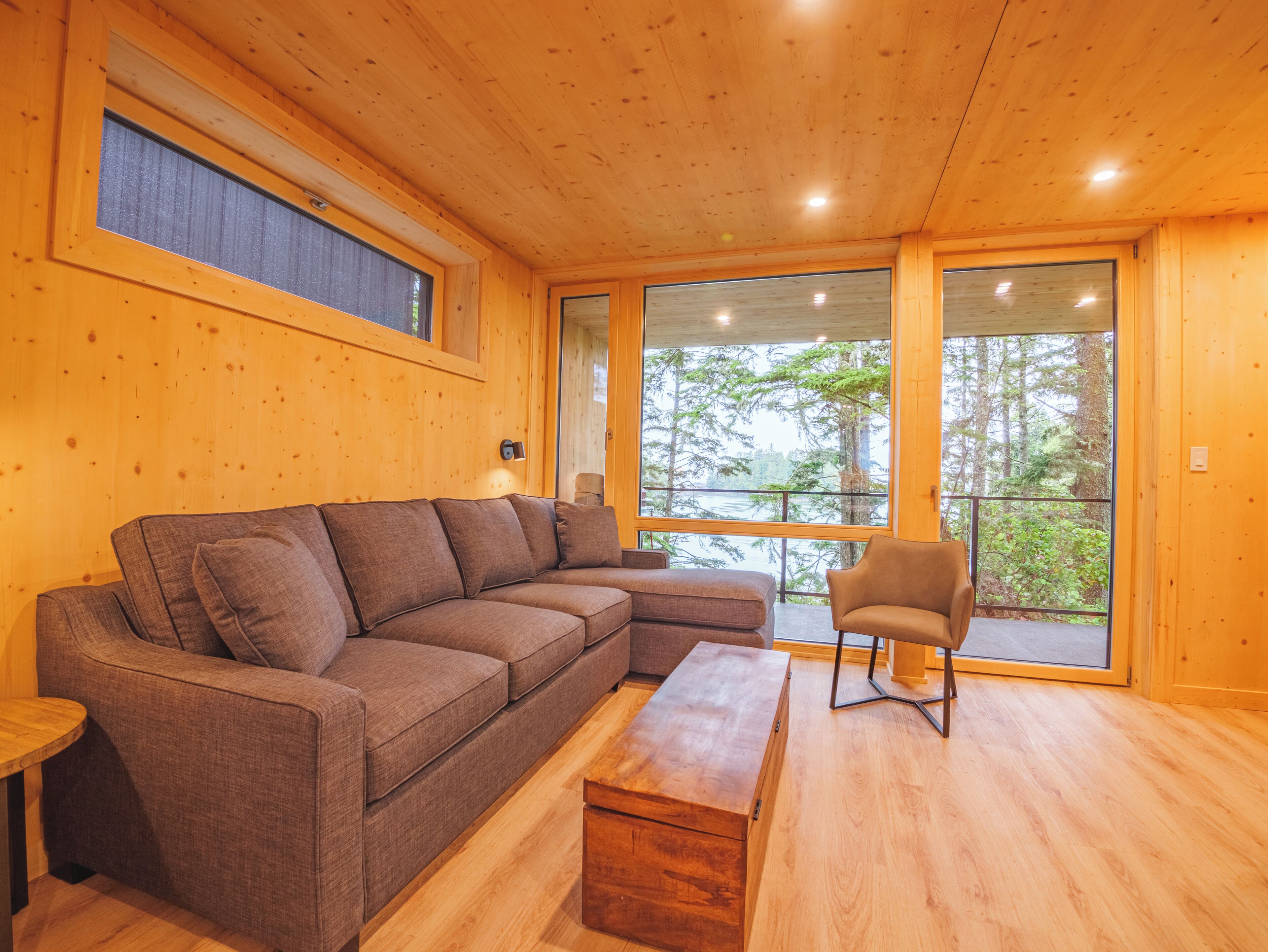 A wooden interior with a sectional sofa, a wooden bench, and a chair.