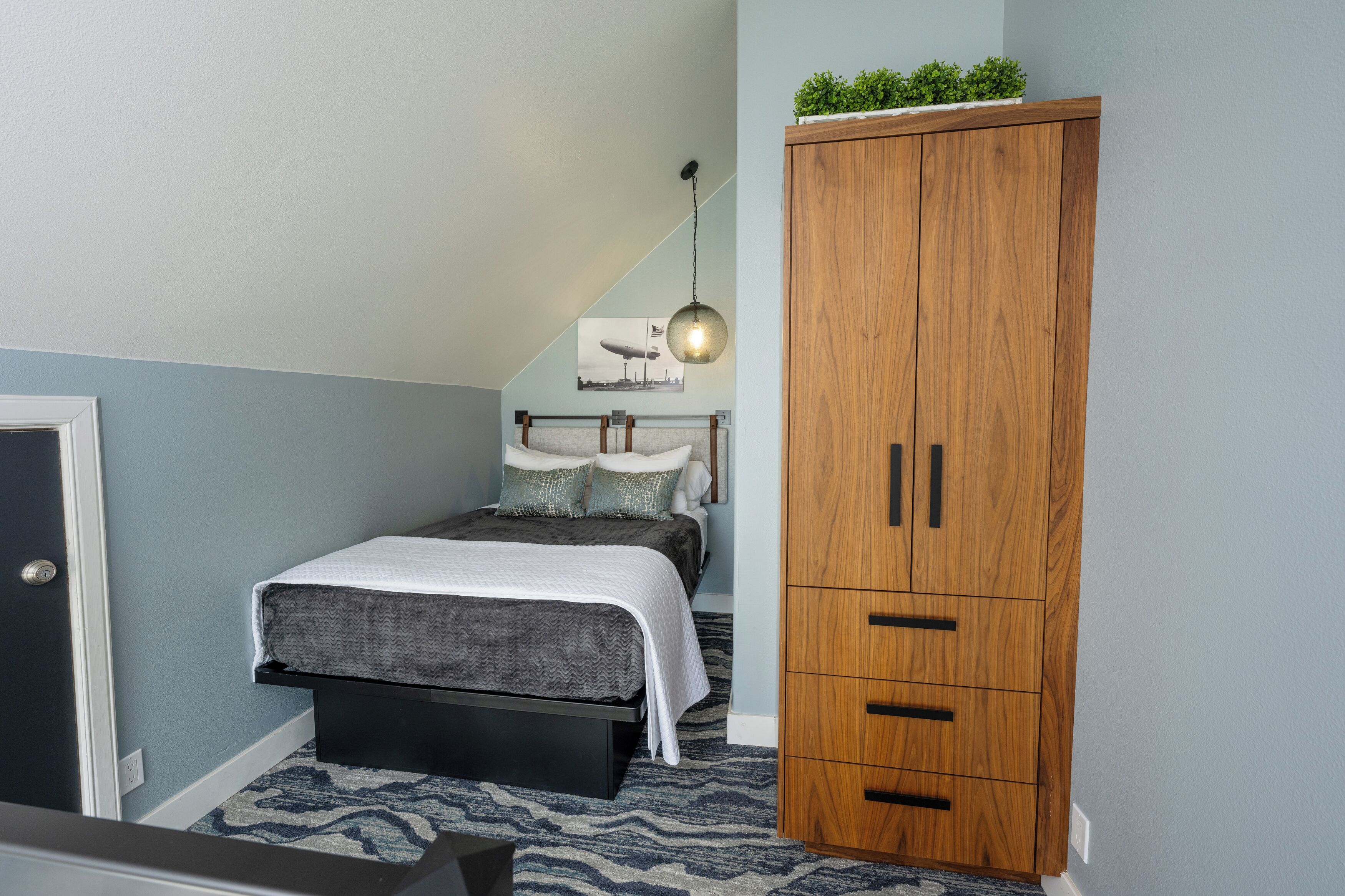 Une chambre à coucher avec un lit, une armoire en bois et un luminaire suspendu.