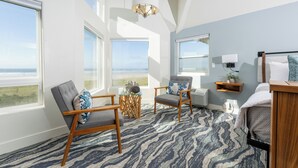 A room with a large window, a bed, a chair, a small table, and a wall-mounted shelf. - Seaside Oceanfront Inn (Seaside)