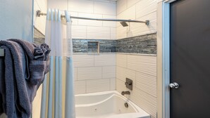 A modern bathroom with a bathtub, shower, and towel rack.