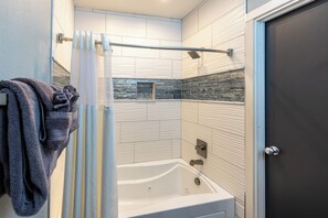 A modern bathroom with a bathtub, shower, and towel rack.