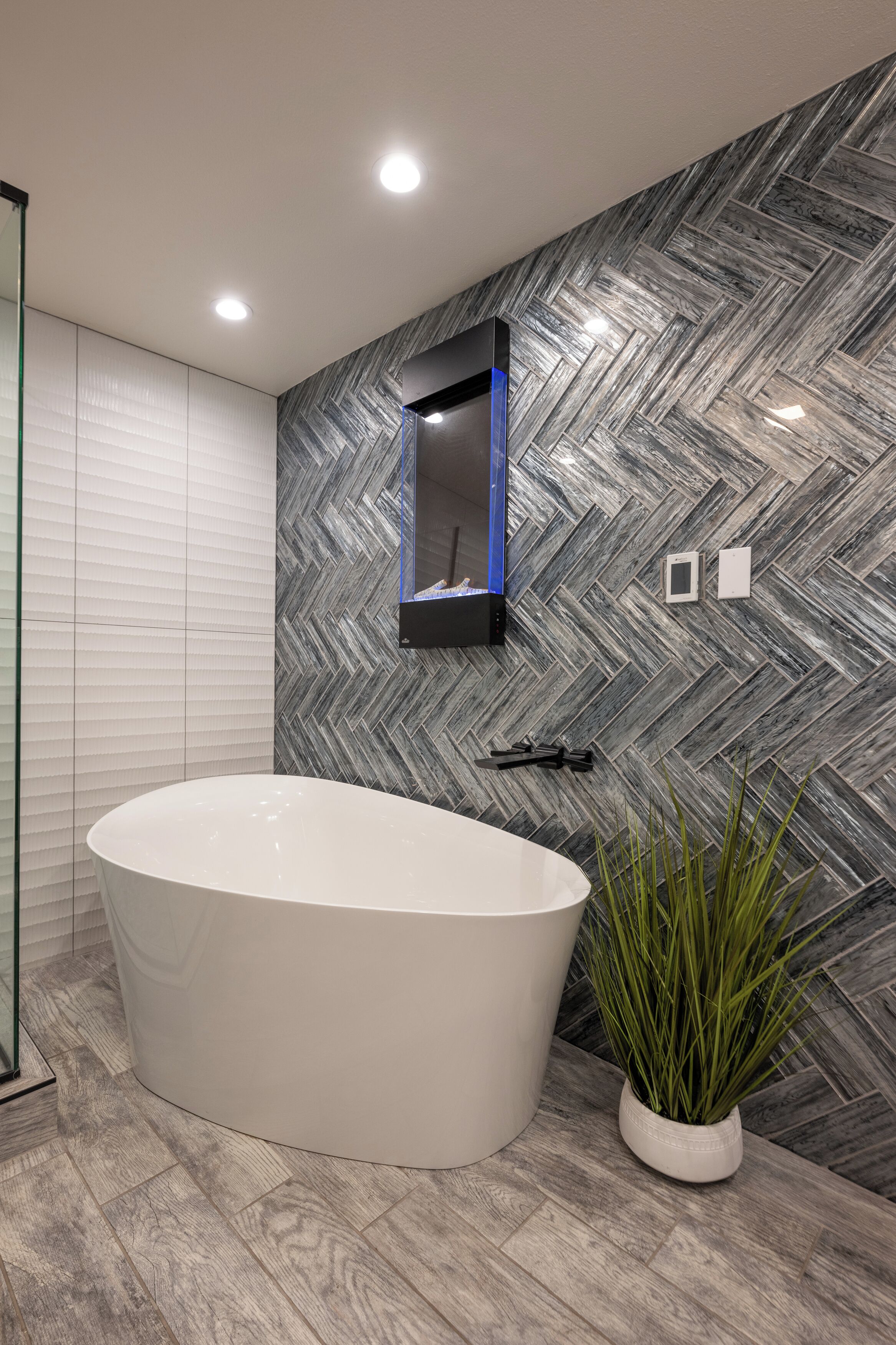 Un baño moderno con una bañera independiente, un espejo y una planta en maceta.