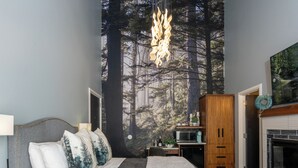 A modern bedroom with a bed, a fireplace, a wardrobe, and a wall mural.