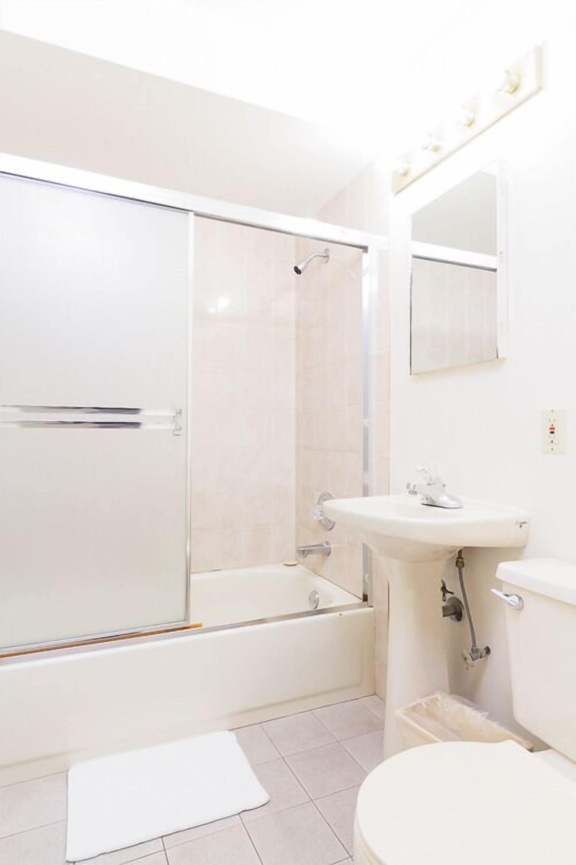 A bathroom with a glass-enclosed shower, a sink, and a toilet.