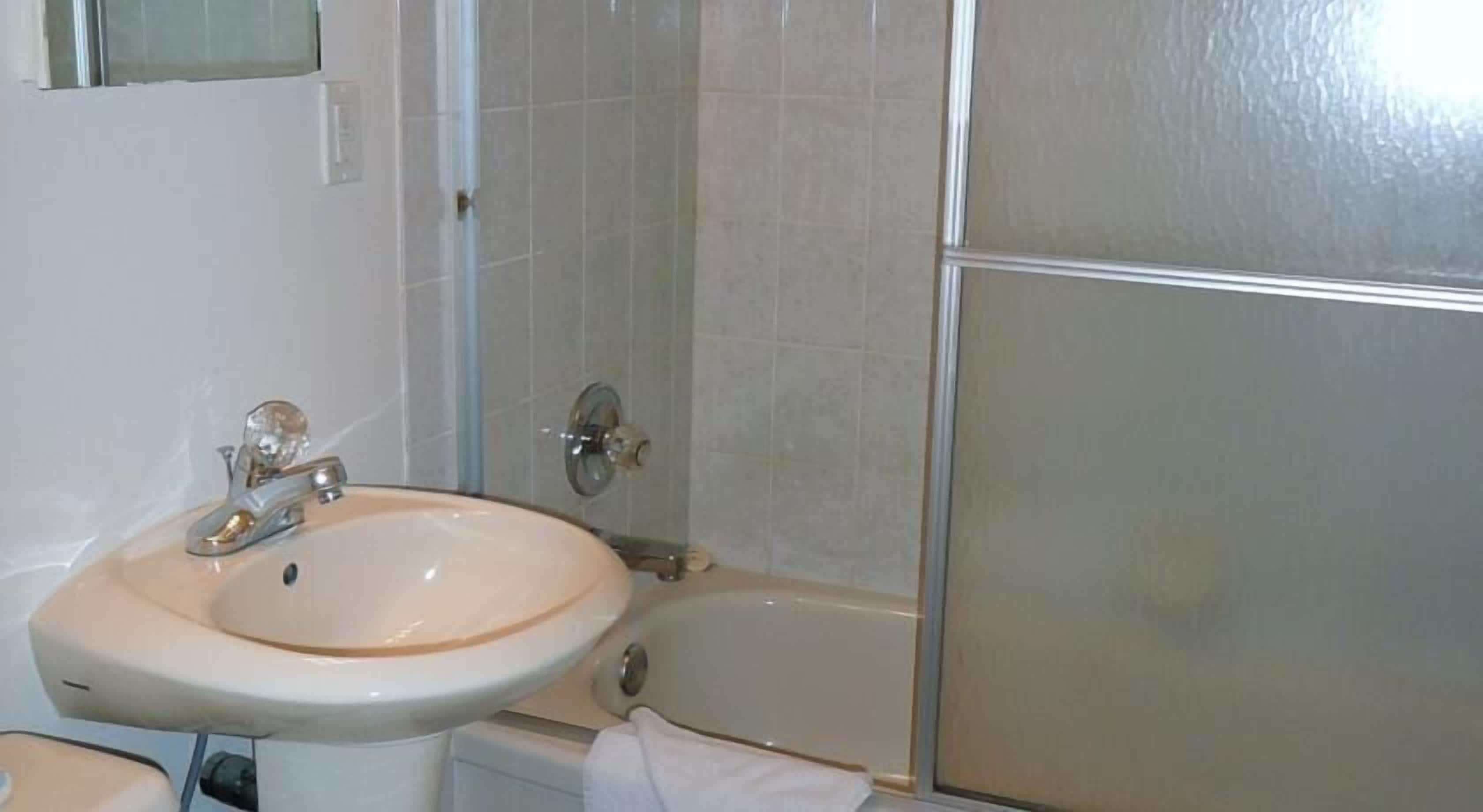 A bathroom with a sink, a bathtub, and a shower area.