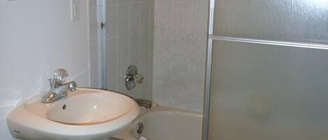 Une salle de bain équipée d’un lavabo, d’une baignoire et d’un espace douche.