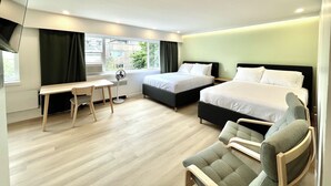 A modern hotel room with two beds, a desk, a chair, and a large window. - English Bay Hotel (Vancouver)