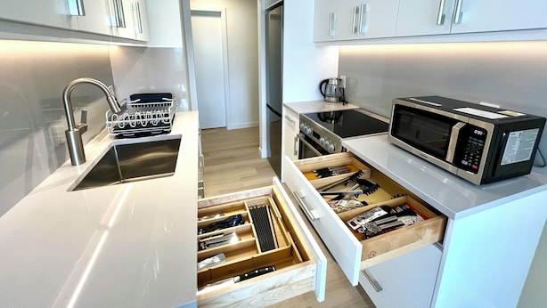 A modern kitchen with white cabinetry, stainless steel appliances, and a built-in drawer organizer. - English Bay Hotel (Vancouver)