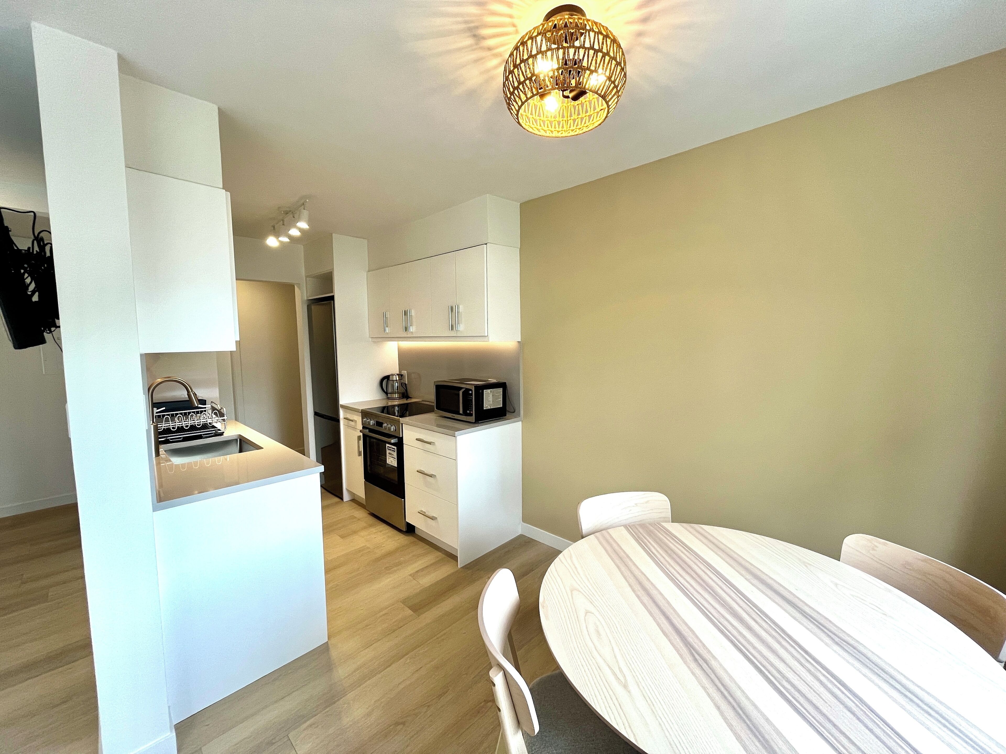 A compact living space with a kitchenette, a dining area, and a separate bedroom.