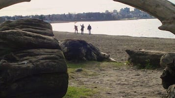 Une arche naturelle qui mène à une plage où se tiennent trois personnes, au bout.