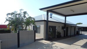 A building with a covered outdoor area, a gated entrance, and potted plants.