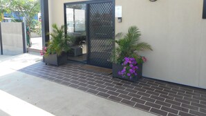 A building entrance with a metal gate, potted plants, and a tiled walkway.
