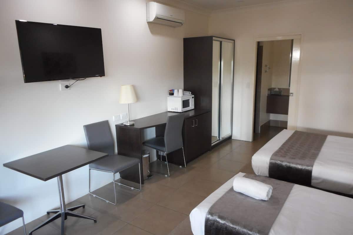 Una habitación de hotel con cama, escritorio, silla, televisión y armario.