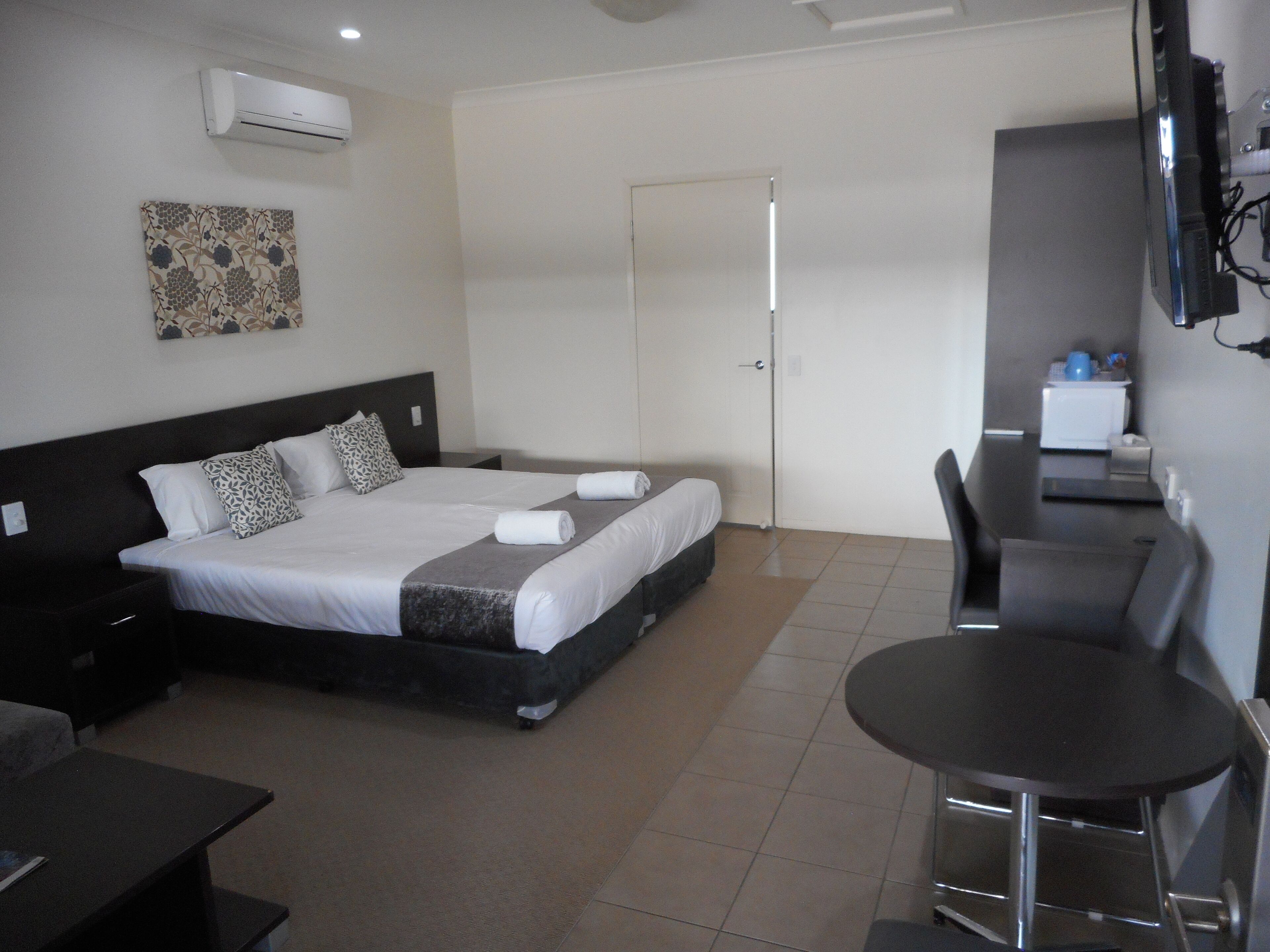 Une chambre d’hôtel comprenant un lit, des tables de chevet, un bureau, une chaise et un téléviseur.
