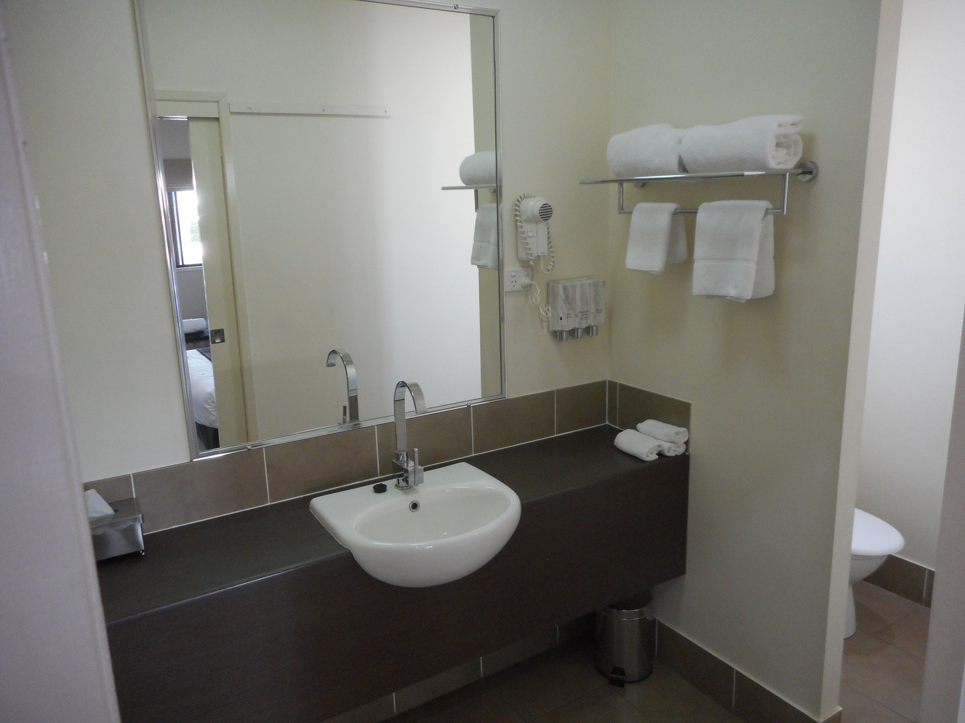 A bathroom with a sink, mirror, towel rack, and toilet.