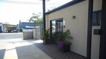 A modern building with a covered driveway, a gated entrance, and potted plants.