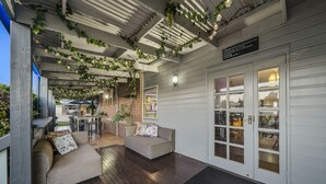 Un espace extérieur aménagé, abrité, avec un canapé et une table, un mur en briques et une porte de garage blanche dotée de panneaux de verre.