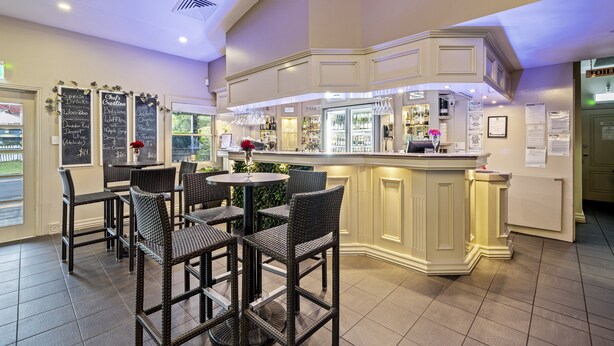 Un espace bar avec des chaises et des tables en osier, un comptoir avec un menu et un réfrigérateur.