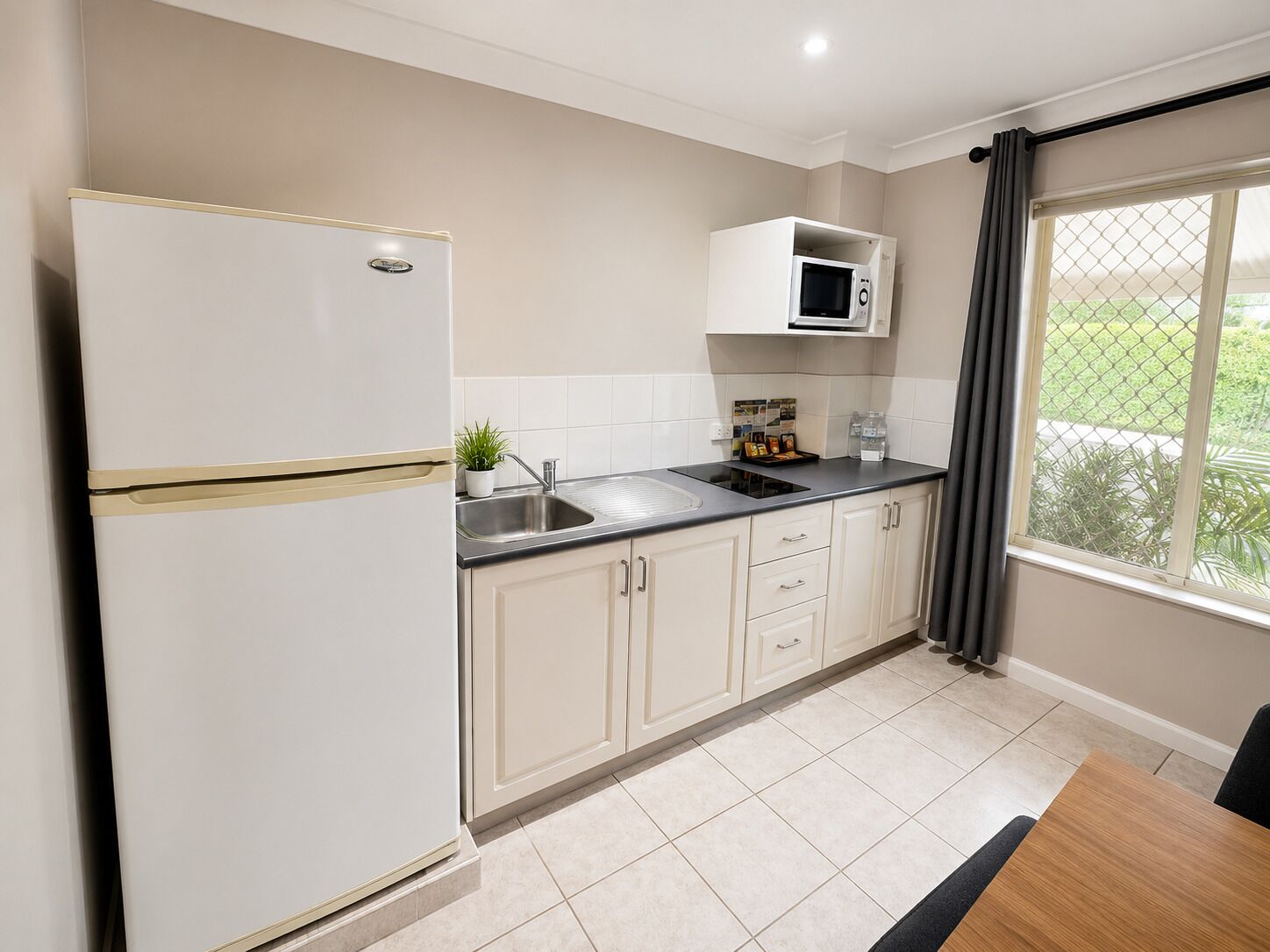 A modern kitchen with a refrigerator, microwave, sink, and cabinets.