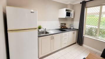 A modern kitchen with a refrigerator, microwave, sink, and cabinets.