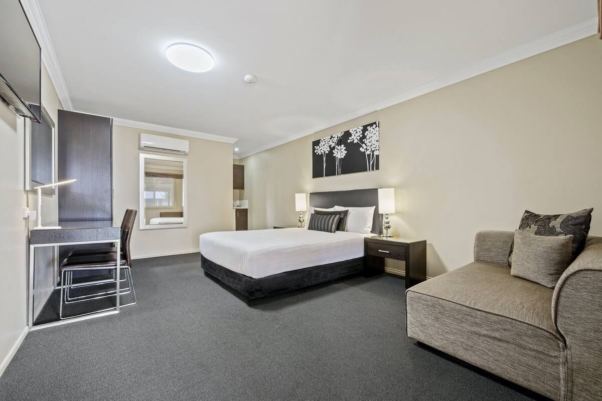A hotel room with a bed, a sofa, a desk, and a chair.