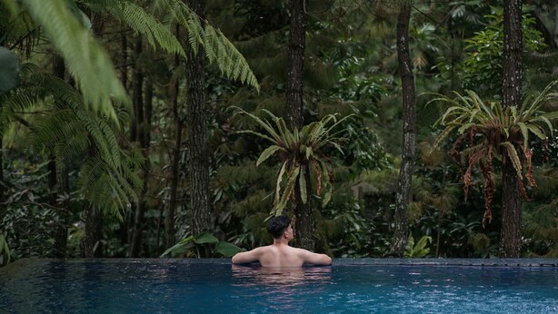 A man in a swimming pool surrounded by lush greenery. - House Sangkuriang (Bandung)