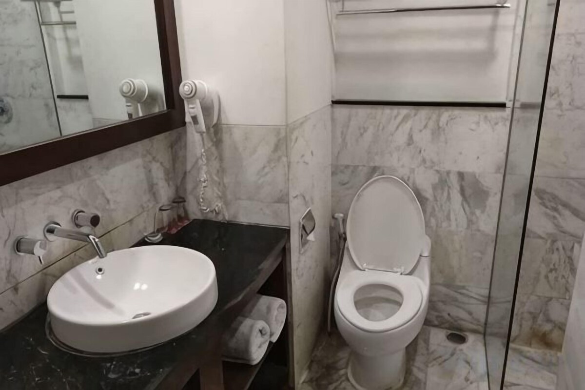 A bathroom with a marble sink, toilet, and a mirror.