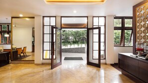 A spacious lobby with a marble floor, a wooden reception desk, and a view of the outdoors through large glass doors. - House Sangkuriang (Bandung)