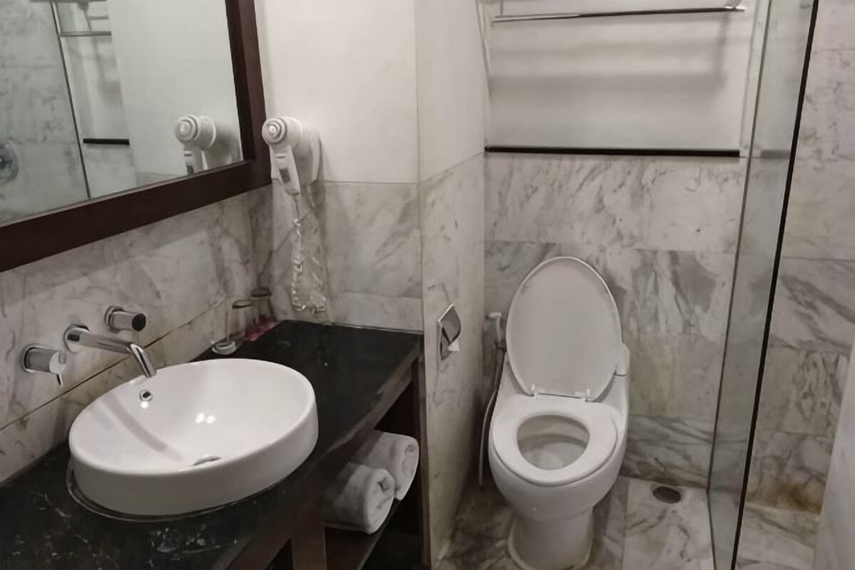 A bathroom with a marble sink, toilet, and a mirror.