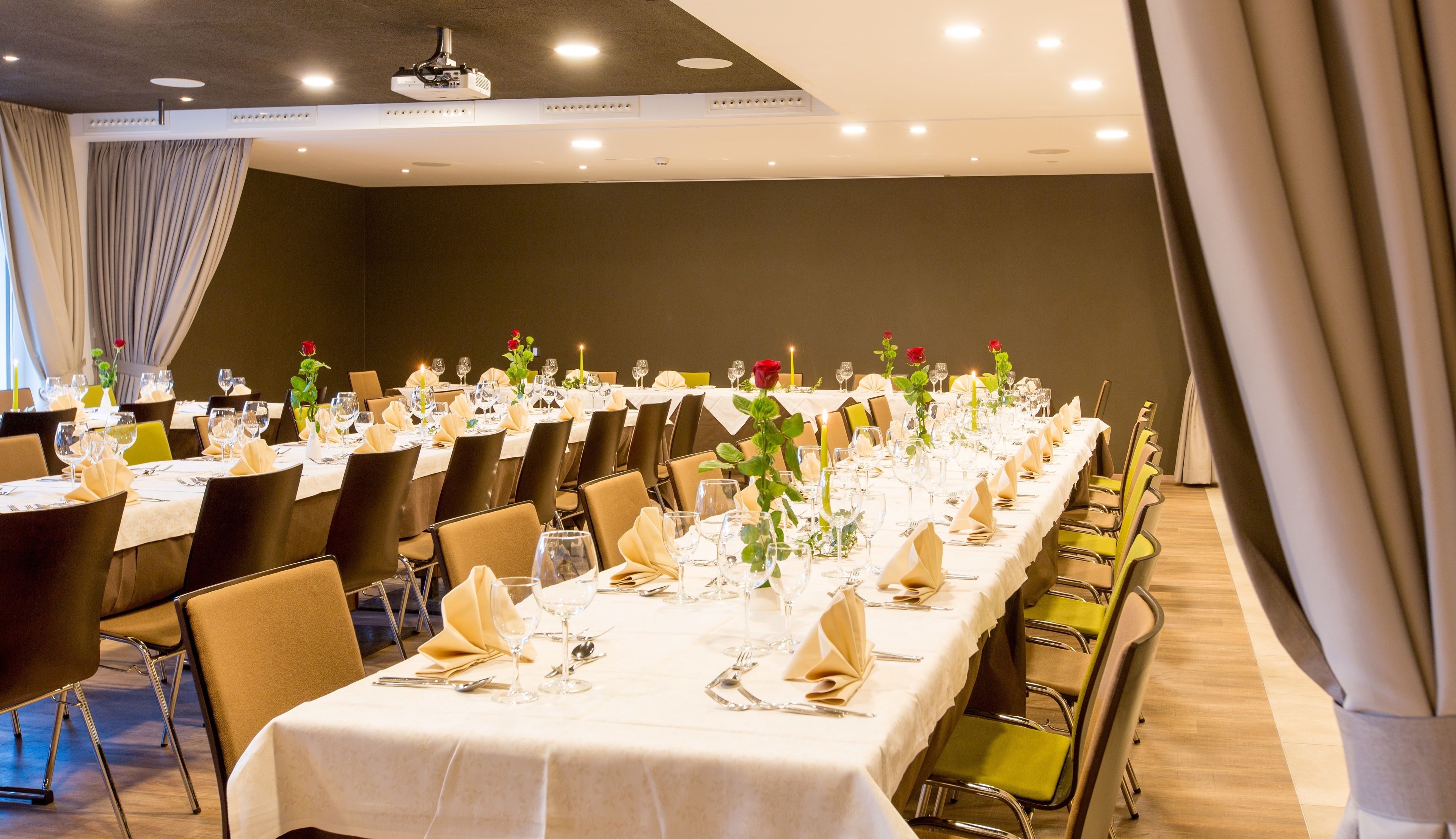A banquet hall with long tables set for dining, equipped with chairs, table settings, and floral centerpieces.
