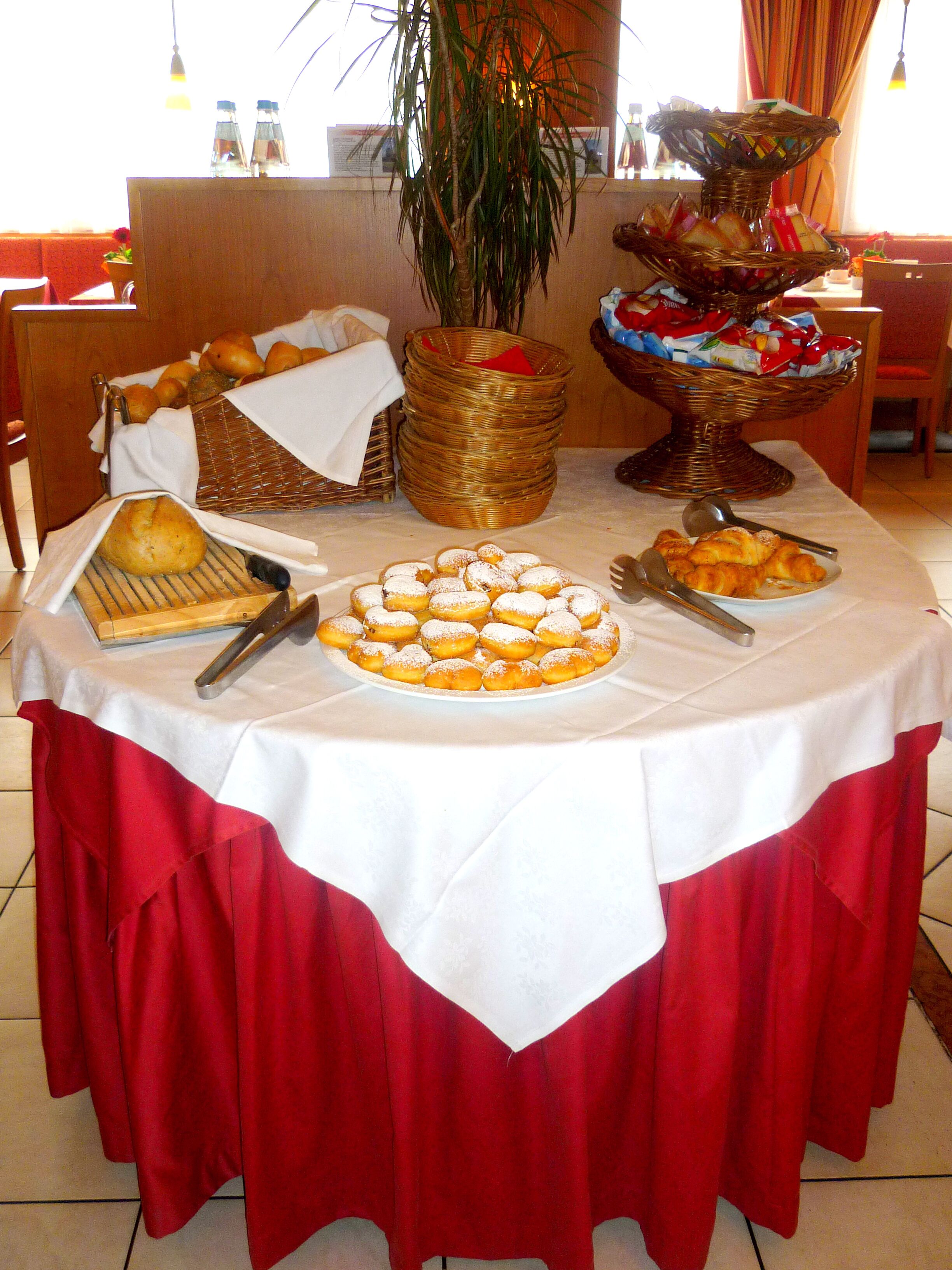 Una mesa de buffet con diversos alimentos, una planta y una cesta de mimbre.