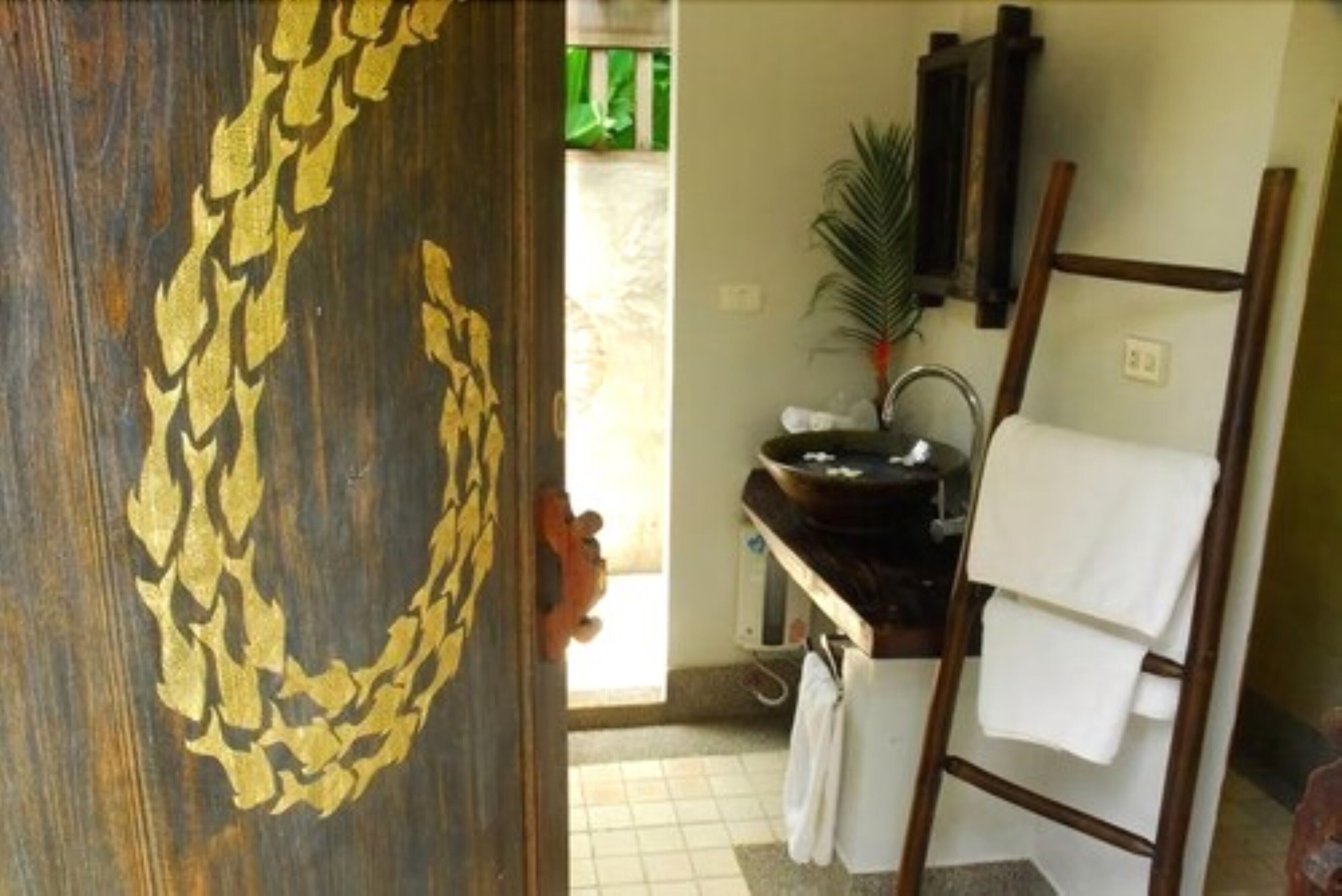 Une salle de bain avec une porte en bois, un lavabo, un porte-serviettes et une échelle.