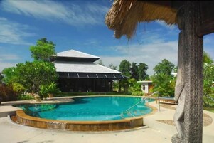 Una piscina al aire libre, sillones reclinables de piscina