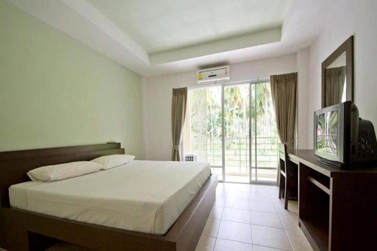 A hotel room with a bed, a TV, and a sliding glass door to the outside.