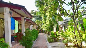 A covered walkway with steps leading to a building with a red roof and a blue awning. - Magic Resort (Koh Samui)