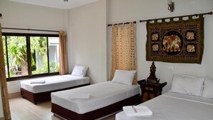 A hotel room with two single beds, a large window with curtains, and a decorative tapestry on the wall. - Magic Resort (Koh Samui)