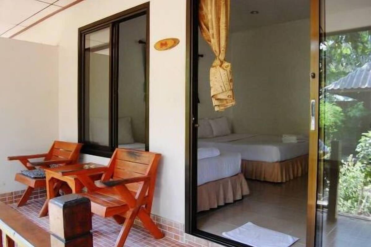 A room with a bed, a window, and a view of greenery outside.