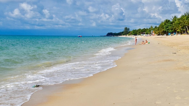 A beach with clear turquoise water, a sandy shore, and palm trees. - Magic Resort (Koh Samui)