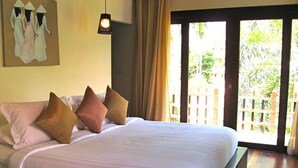 A bedroom with a large bed, a painting on the wall, and a view of greenery outside. - Baan Chaba Samui (Koh Samui)