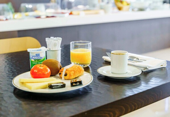 A breakfast setting with a plate of food, a glass of orange juice, a cup of coffee, and a bottle of milk.