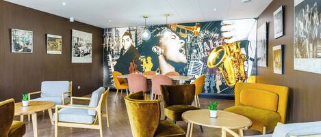 A modern lounge area with a mural, comfortable seating, and a herringbone floor pattern.