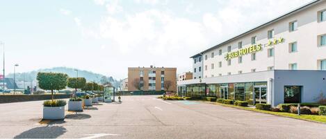 A B&B hotel with a modern facade, a parking lot, and a clear sky.