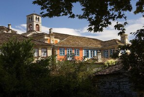 A traditional building with a bell tower, stone walls, and a mix of colorful facades. - Archontiko Dilofou (Zagori)