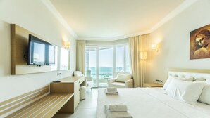 Een hotelkamer met een groot bed, een aan de muur bevestigde televisie, een bureau, een stoel en uitzicht op de omgeving.