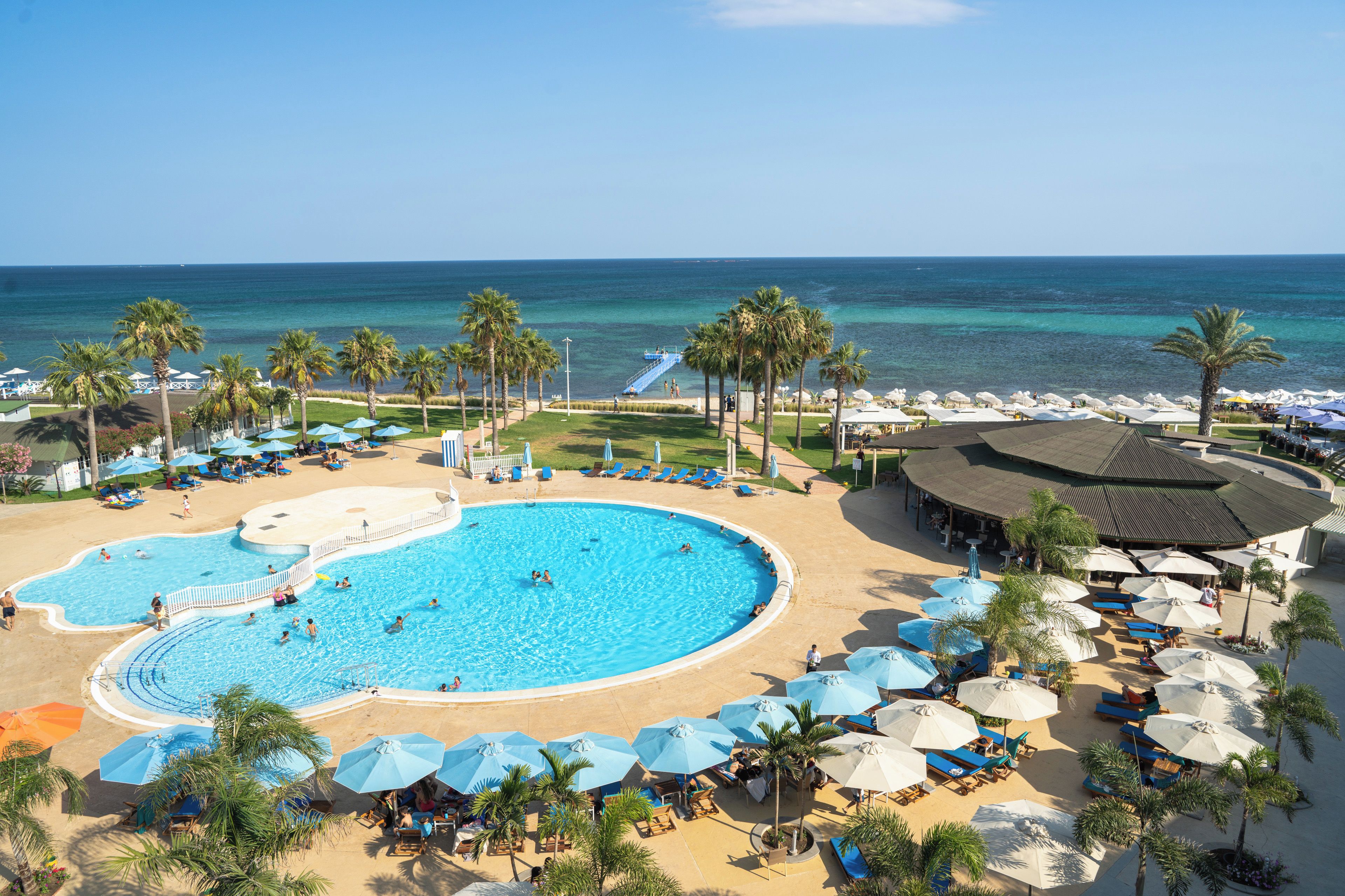 Un resort con una gran piscina, zona de playa y vista al océano.