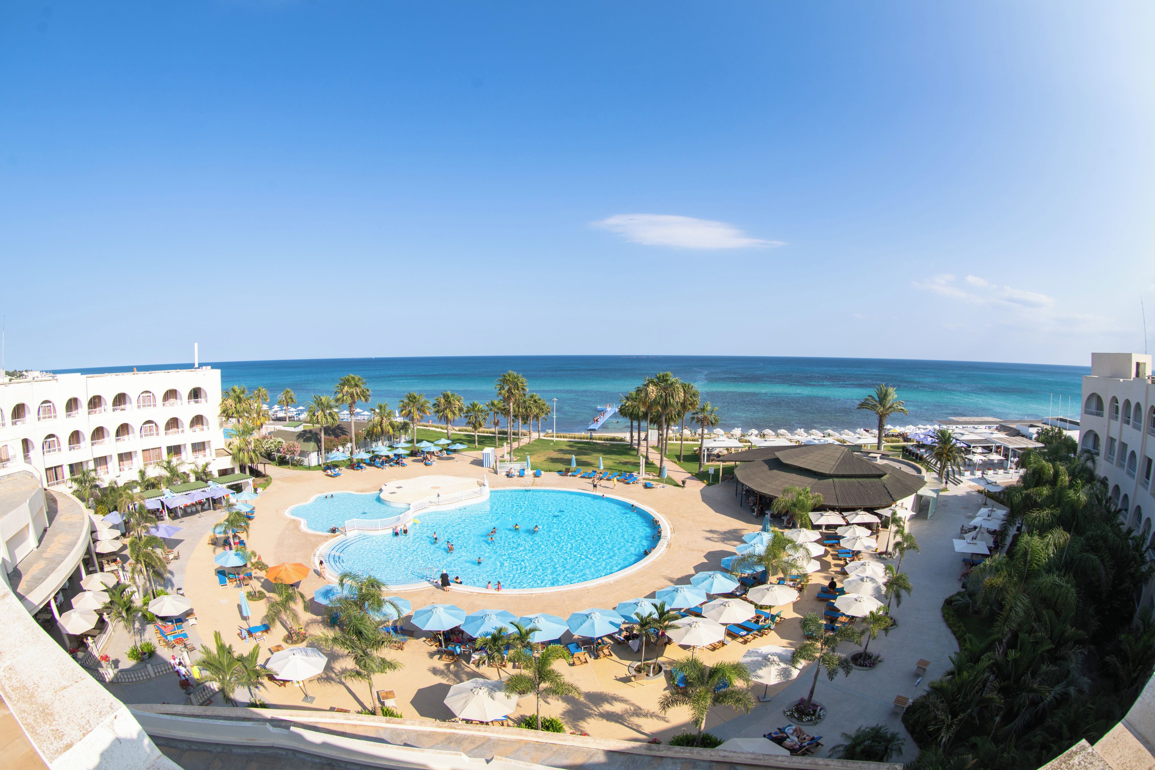 Un resort con piscina central, tumbonas y zona de playa.