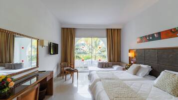 Quarto de hotel com cama, escrivaninha, cadeira, televisão e janela com cortinas.