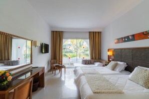 Una habitación de hotel con cama, escritorio, silla, televisor y ventana con cortinas.