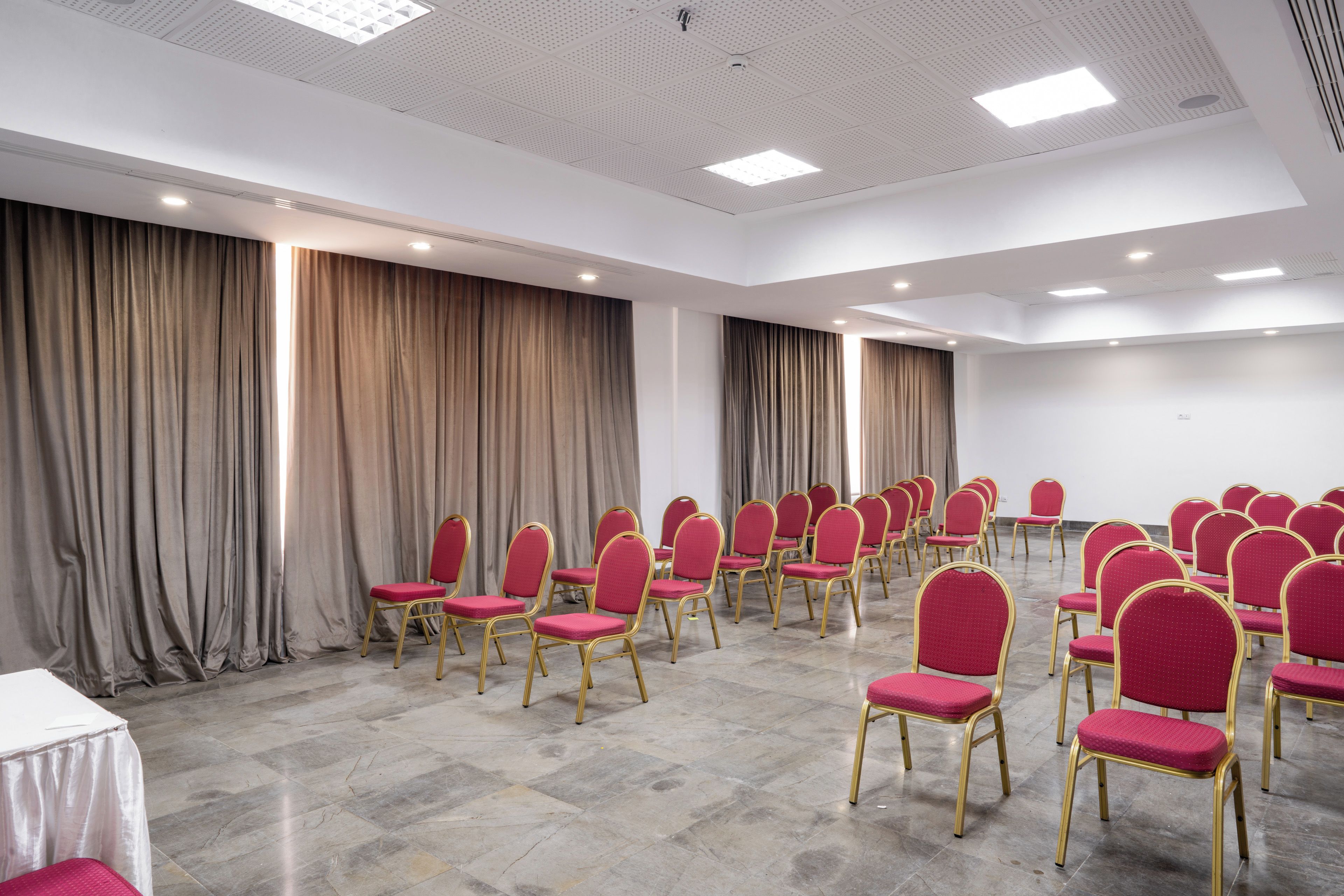 Una sala conferenze con file di sedie rosse e una lavagna.